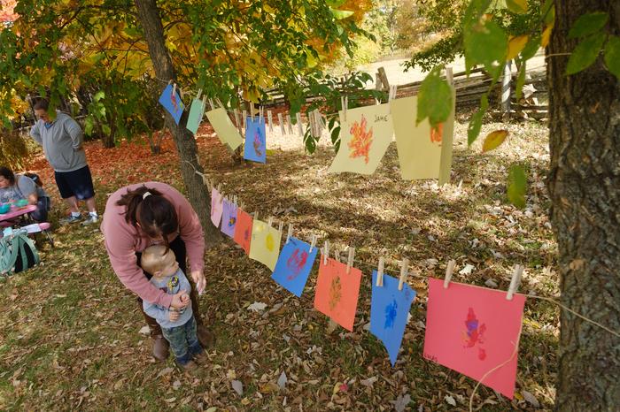 A woman and child look at leaf crafts that kids made at the UK Arboretum.