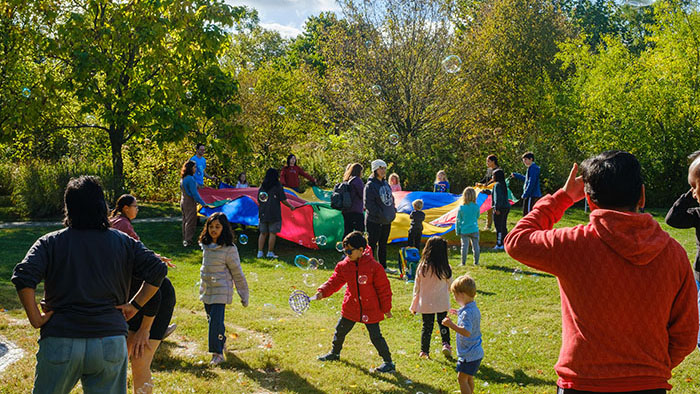 Kids playing with bubbles and a parachute in the Kentucky Children's Garden
