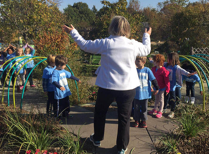 A woman leads a group of children through the Kentucky Children's Garden