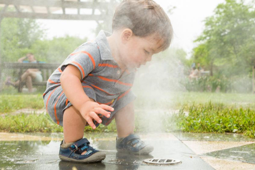 A child plays in a water feature at the KCG